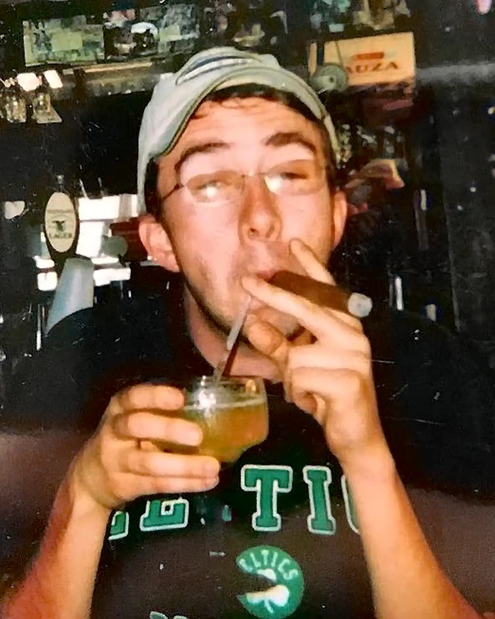 Celtics Shirt, Cigar, and Alcohol | Joe List | Tuesdays with Stories Comedian Joe List of Tuesdays with Stories in a Boston Celtics shirt, with a cigar in one corner of his mouth and a straw to an alcoholic beverage in another. Find more about Joe List at www.tuesdayspod.com/joe-list