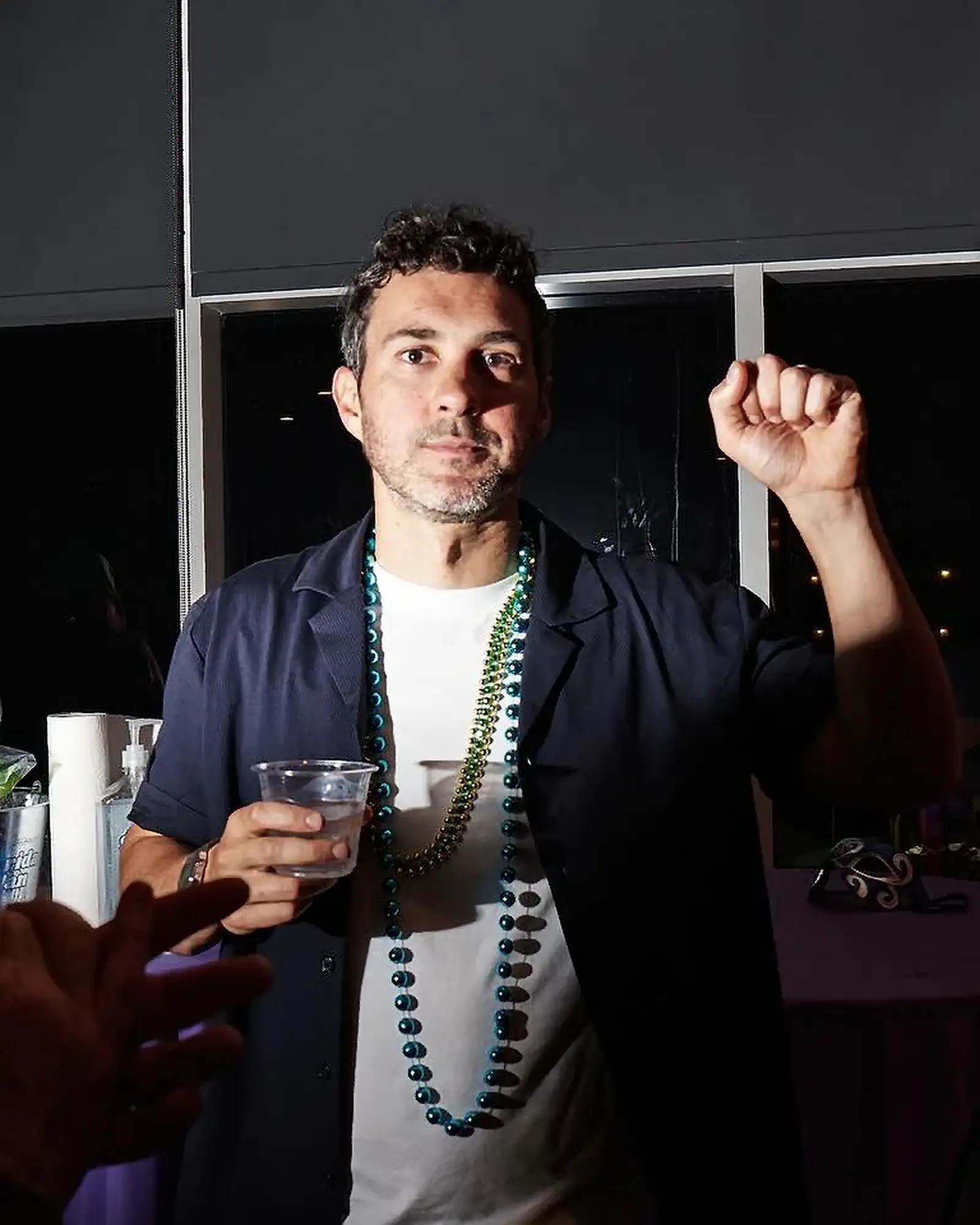 Mark Fist and Beads | Mark Normand | Tuesdays with Stories Comedian Mark Normand of Tuesdays with Stories raising his fist while wearing beads. Find more about Mark Normand at www.tuesdayspod.com/mark-normand